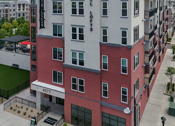 A multi-story building with a red and white facade and the words "Parkhill Lofts" on the side.