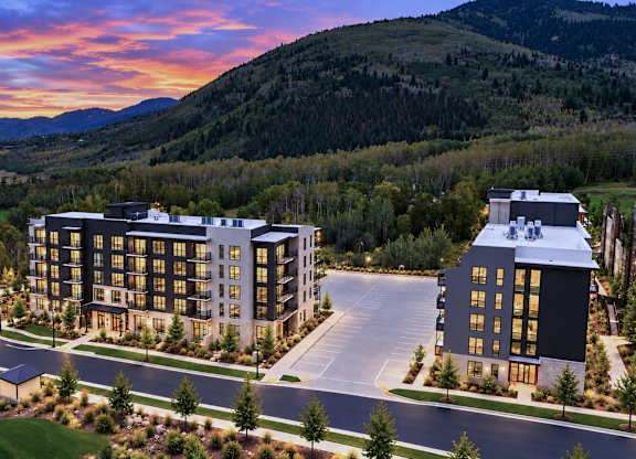 A large hotel complex with a parking lot in front of it.