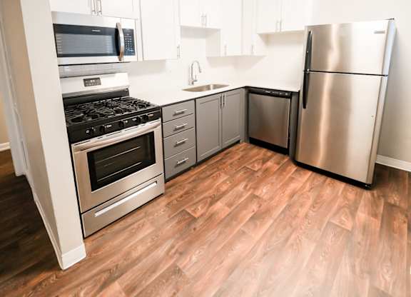 A kitchen with a stainless steel refrigerator, oven, and microwave.