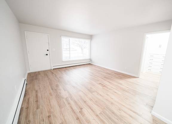 A room with wooden flooring and white walls.