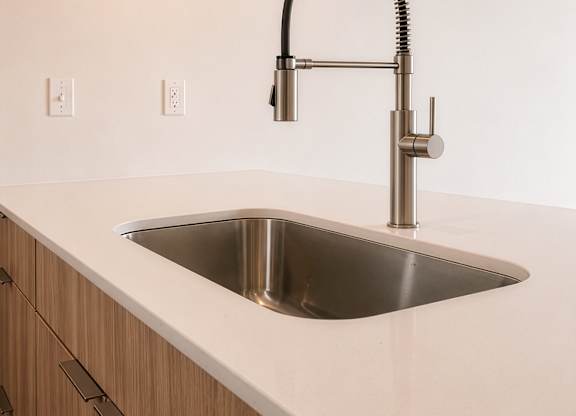 A modern kitchen with a stainless steel sink and wooden cabinets.