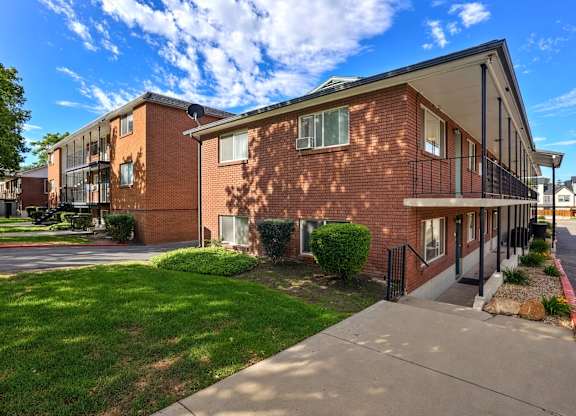 A red brick apartment building with a green lawn in front.
