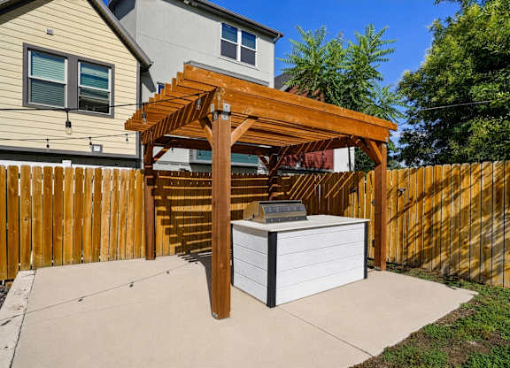 A wooden pergola is attached to a white box.