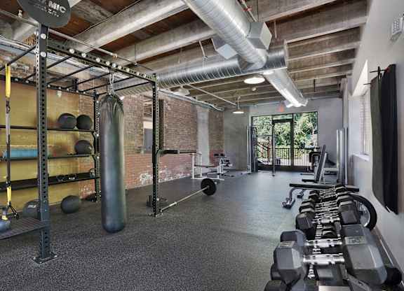 A gym with a variety of equipment including dumbbells, kettlebells, and weight plates.