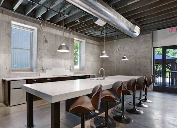 A long table with chairs is in a room with a concrete wall.