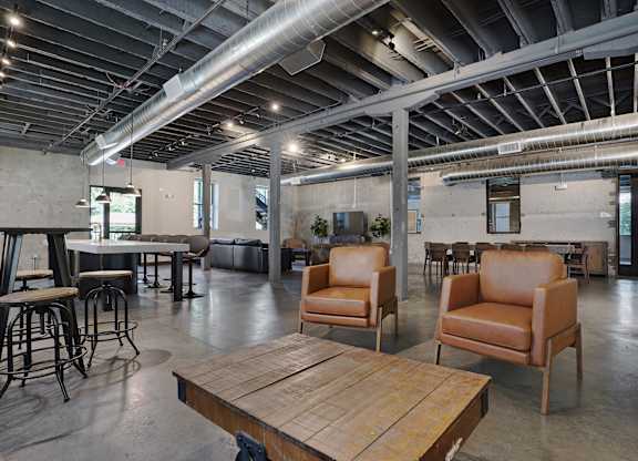 A large room with a wooden table and leather chairs.