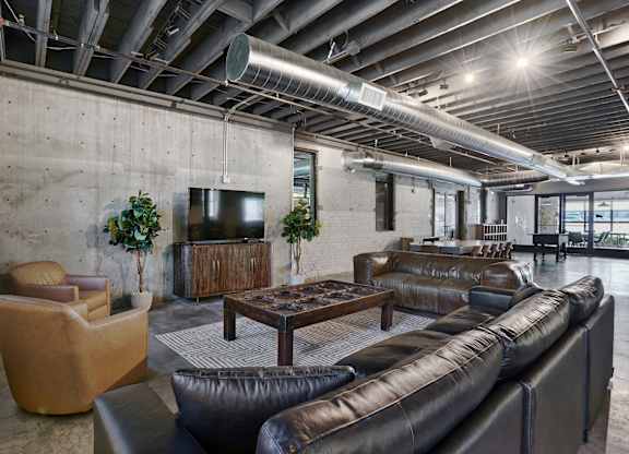 A modern living room with a brown leather couch and a wooden cabinet.