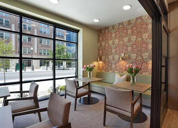 A room with a table and chairs with a window overlooking a street.