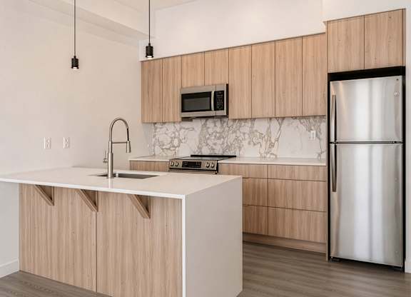 A modern kitchen with a white countertop and wooden cabinets.