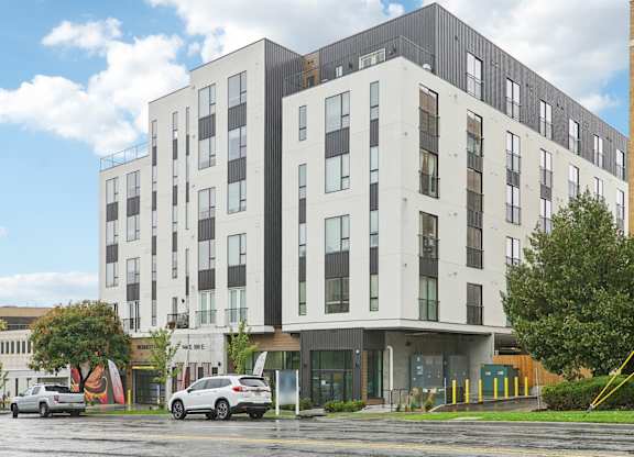 A modern multi-story building with a parking lot in front.