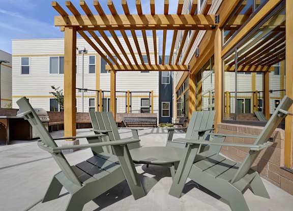 A wooden pergola with green chairs and a table in the foreground.