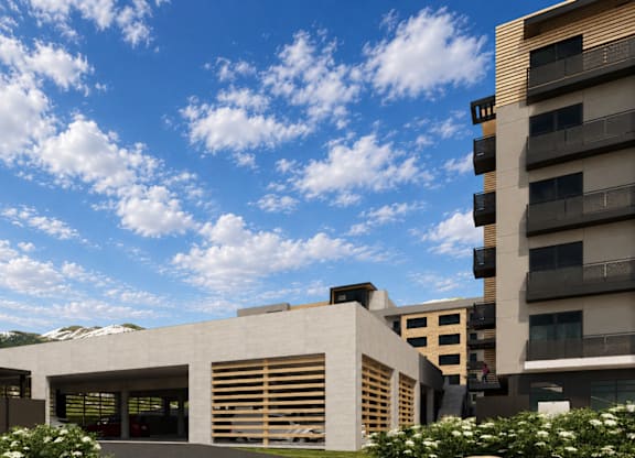 A modern building with a large garage door is surrounded by other buildings and greenery.