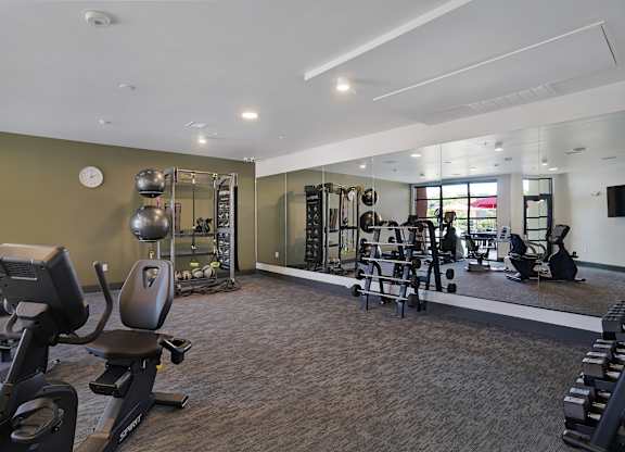A gym with a variety of equipment including treadmills, weights, and exercise machines.
