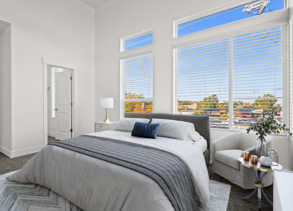 a bedroom with a bed and three large windows