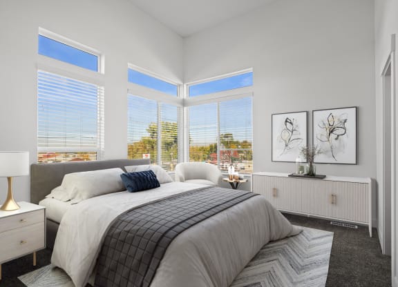 a bedroom with a large bed and three large windows