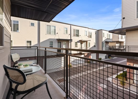a balcony with a table and chairs and a view of apartment buildings