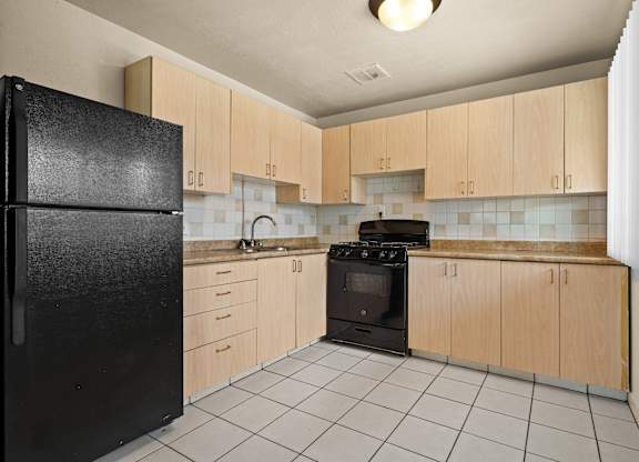 A kitchen with black appliances and wooden cabinets.