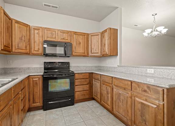 A kitchen with wooden cabinets and a black stove top oven.