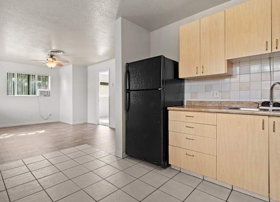 A kitchen with a black fridge and wooden cabinets.