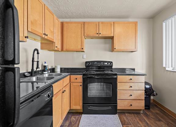 A kitchen with wooden cabinets and black appliances.