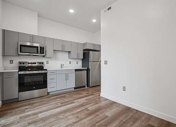 A modern kitchen with stainless steel appliances and wooden flooring.