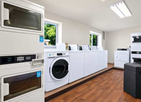 A row of white appliances in a room with wooden floors.