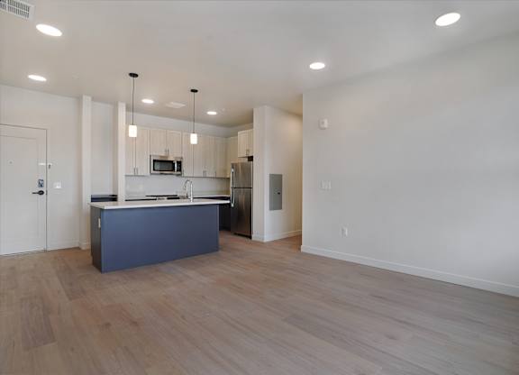 A kitchen with a blue island and wooden floors.