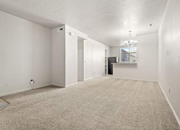 A spacious room with a carpeted floor and white walls.