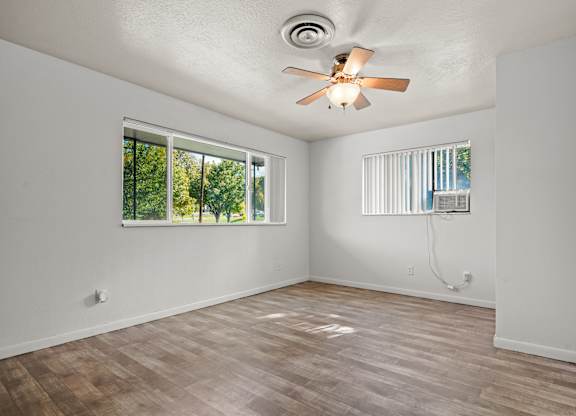 A room with a ceiling fan and wooden flooring.