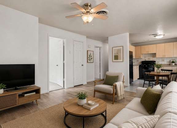 A living room with a white couch, a coffee table, and a flat screen TV.