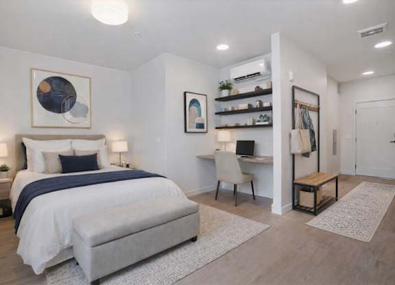 A bedroom with a large bed, a desk with a chair, and a rug on the floor.