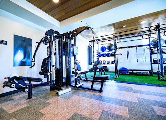 A gym with a variety of equipment including a leg press machine, a cable machine, and a bench press.