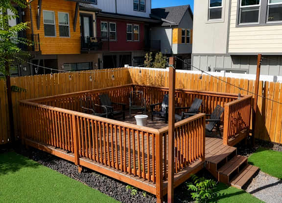 A wooden deck with a hot tub in the middle of a grassy area.