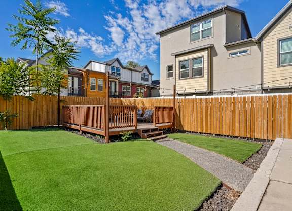 A backyard with a wooden fence and a green lawn.