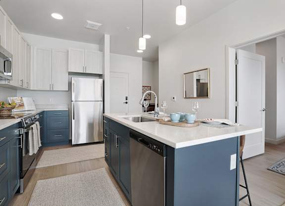 A kitchen with a white counter top and blue cabinets.