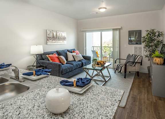A modern kitchen with a grey granite countertop and a grey and white rug.