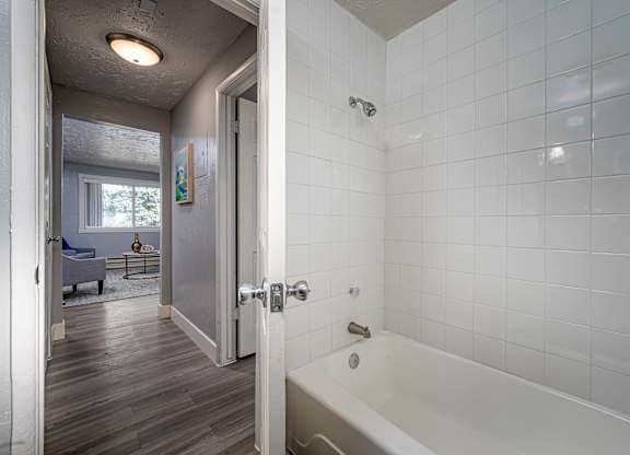 a bathroom with white tile and a white bathtub