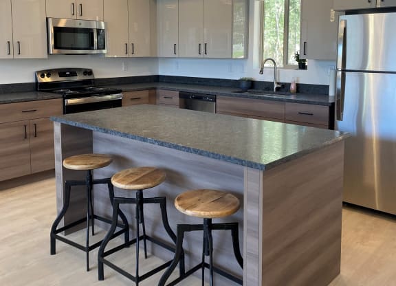 a kitchen with a large island with three stools
