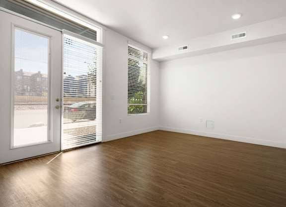 an empty living room with a door to a balcony