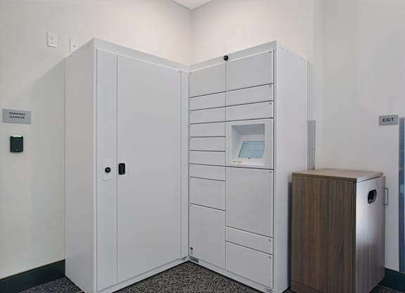 A white storage unit with a door open and a trash can to the side.