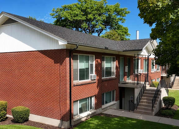 A red brick house with a green lawn in front.