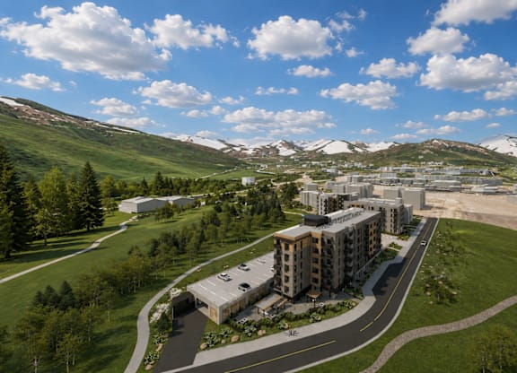 A large building complex is surrounded by a green landscape and a road.