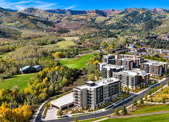 A large building complex is surrounded by a grassy area and trees.