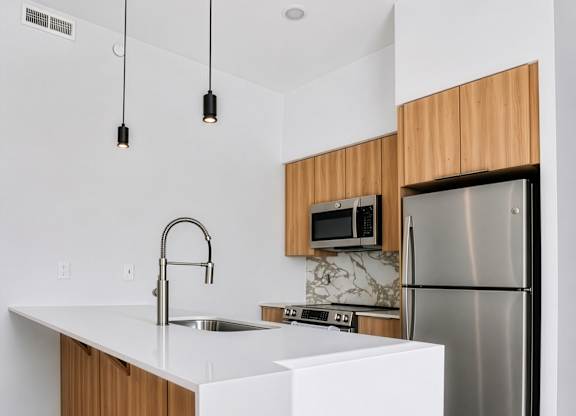 A modern kitchen with a white countertop and wooden cabinets.