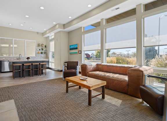 a living room with a couch and a coffee table and a kitchen with large windows