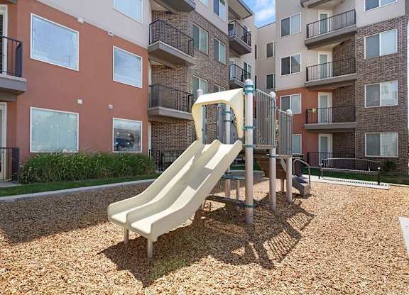 A playground with a slide in front of apartment buildings.