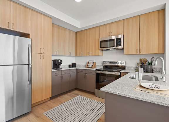 a kitchen with stainless steel appliances and wooden cabinets at SPARK Apartments, Salt Lake CIty, UT