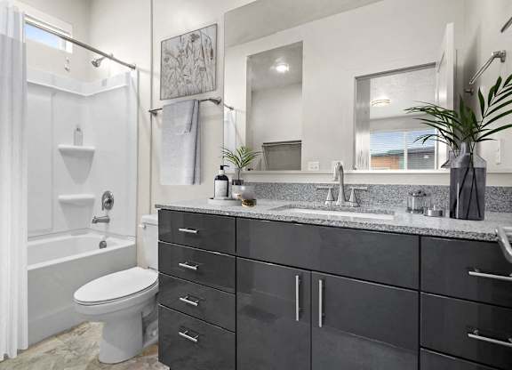 A bathroom with a white toilet, a white shower curtain, and a black cabinet.