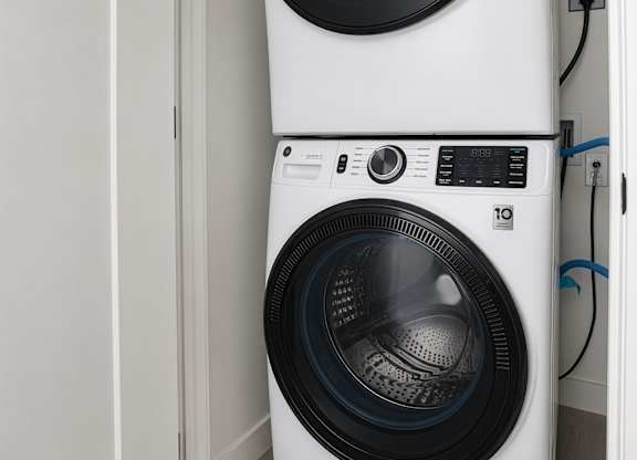 A white washing machine is stacked on top of another white washing machine.