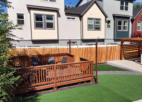 A backyard with a wooden deck and a green lawn.